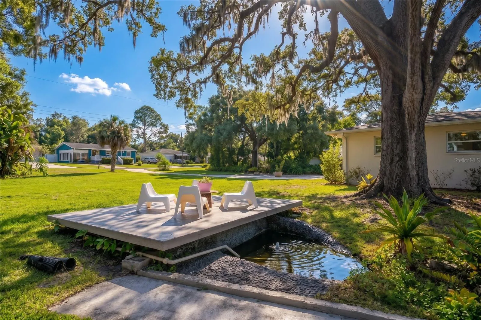 A private manicured spring with a patio perched in the shade of mature landscaped trees.