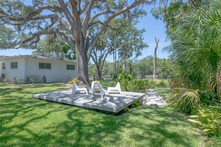 A private manicured spring with a patio perched in the shade of mature landscaped trees.
