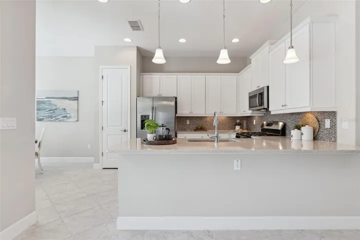 11'6" x 13'6" Kitchen area w/ breakfast bar, pendant lighting & Listello backsplash