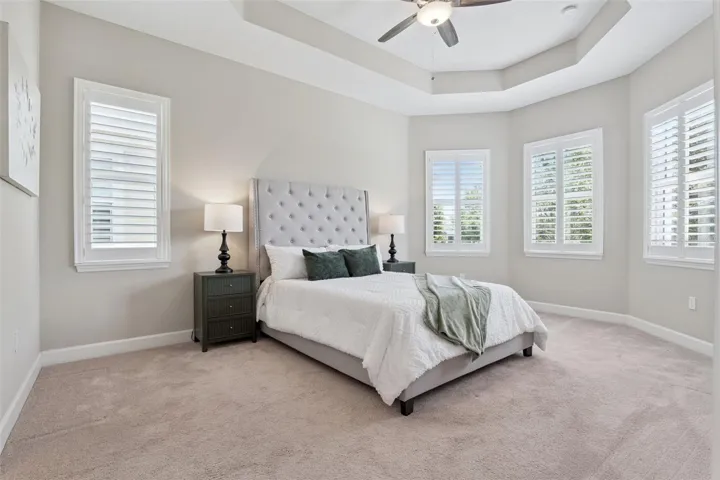12' x 17'6" Primary Bedroom w/ tray ceiling, Plantation style shutters & a ceiling fan