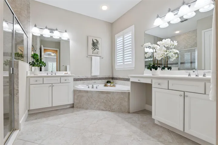 12' x 11' Primary Bathroom w/ separate vanities, corner soaking tub & a glass enclosed walk-in shower