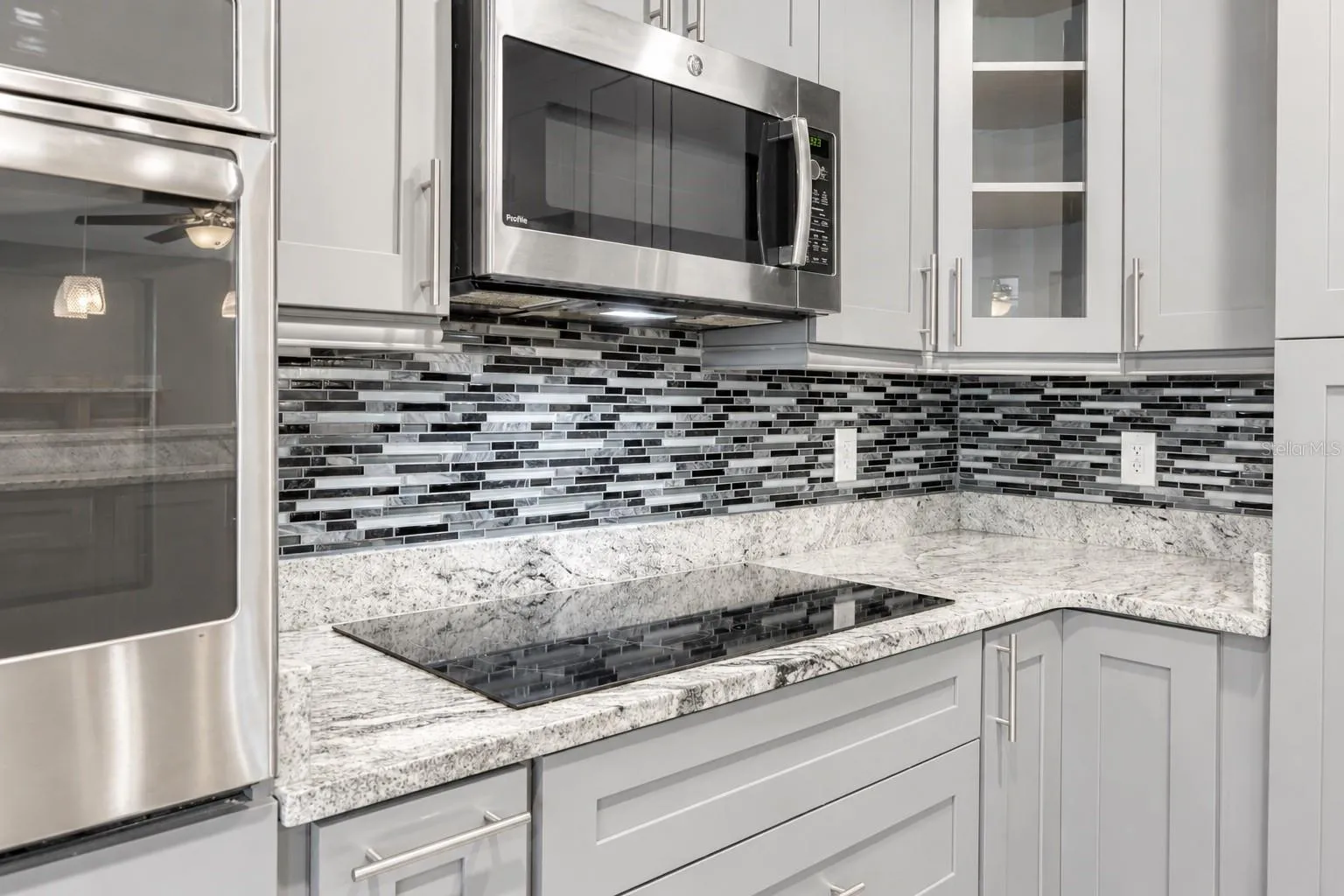 Gourmet Island Kitchen With Granite Countertops & Stainless Steel Appliances & Cooktop Stove.