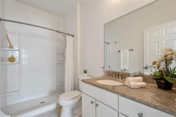 Primary bathroom with walk in shower, granite countertops, updated lighting.