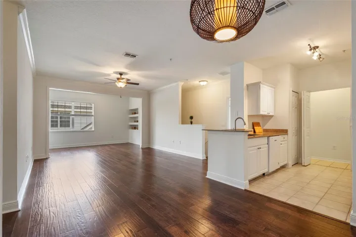Broader view from dining area looking into living, alcove , kitchen and staircase to right.