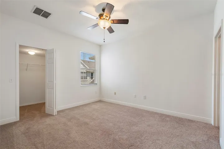 2nd Bedroom with walk in closet and ceiling fan, blinds on window.