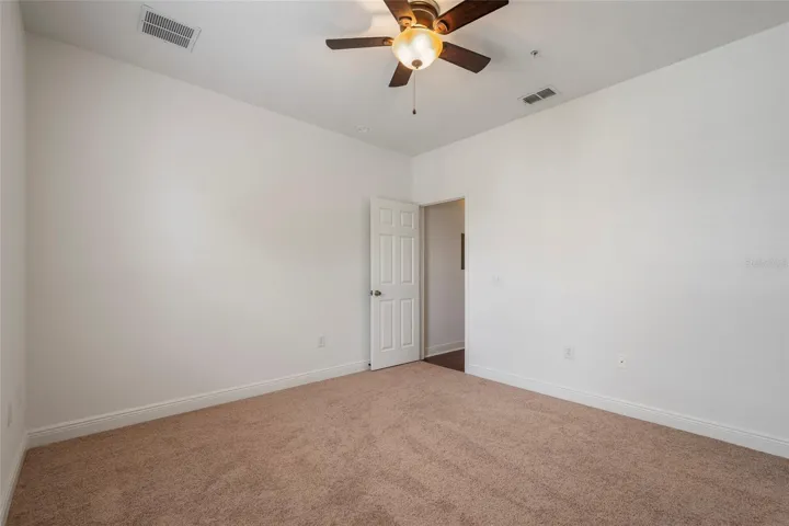 2nd bedroom view looking back at entry door. New ceiling fan, carpet and fresh paint.