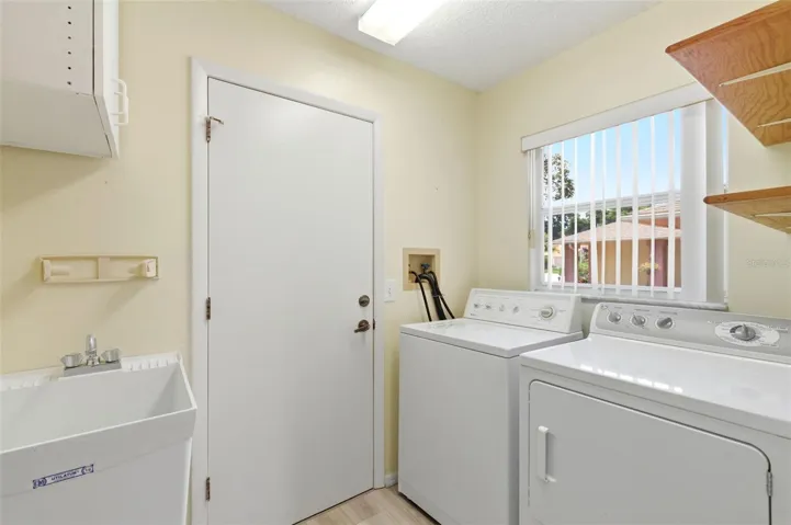 Inside laundry room with utility sink, leading to the garage