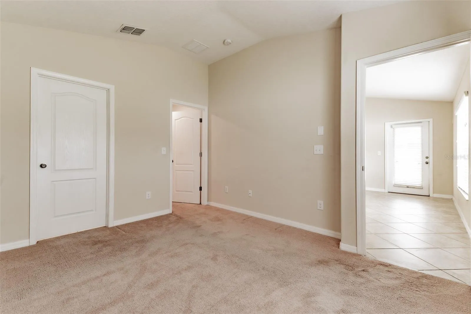 Primary bedroom looking to patio door. Bath on left and walk in closet to right of bathroom.