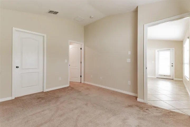 Primary bedroom looking to patio door. Bath on left and walk in closet to right of bathroom.