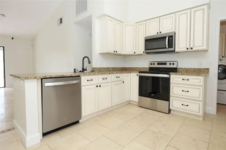 Spacious kitchen with travertine tile flooring, granite countertops and stainless steel appliances.