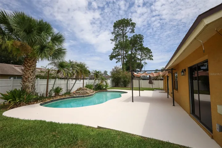 Rear yard with an open-air sparkling pool with space for the kids and pets to play.