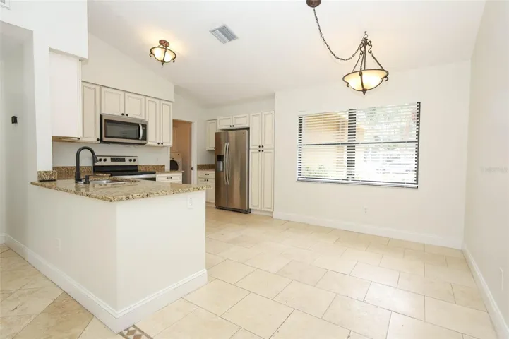 Spacious kitchen with travertine tile flooring, granite countertops and stainless steel appliances.