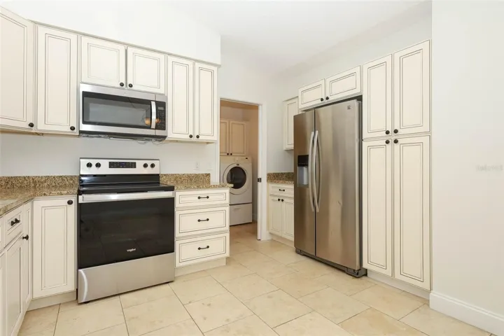 Spacious kitchen with travertine tile flooring, granite countertops and stainless steel appliances.