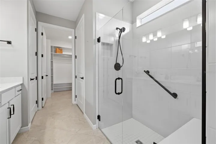Primary en suite with seamless glass shower stall and bench