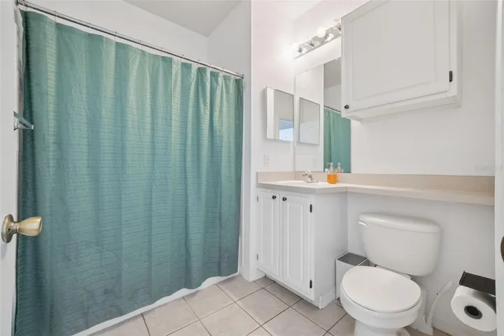 Tub shower combo in bathroom with additional cabinetry for storage.