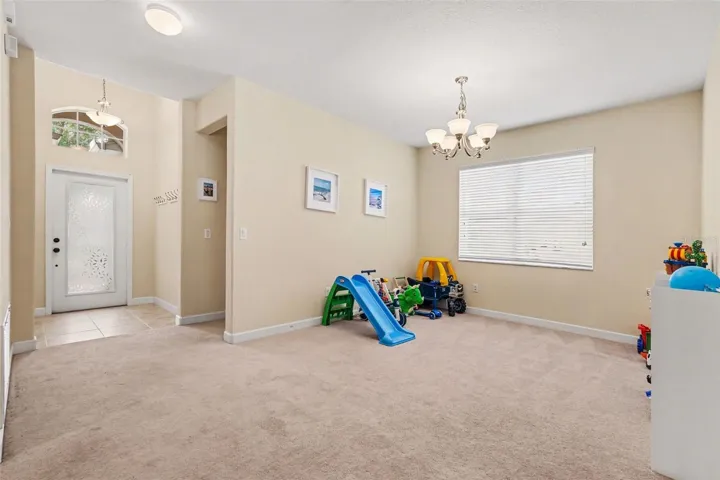 Large flex space with chandelier and open view toward foyer entry. Adaptable as formal living, or hobby/game space in Tampa FL 33647. Junior suite to the far right