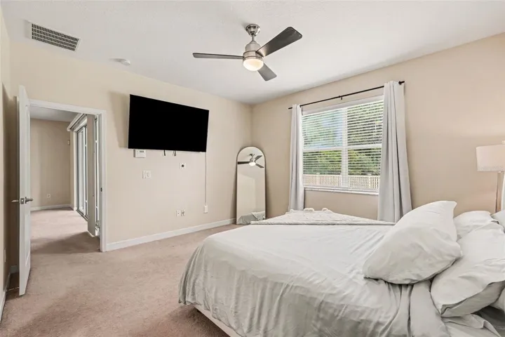 Primary bedroom suite with en-suite bathroom, ceiling fan, and natural light in Tampa FL 33647