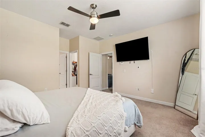 Primary bedroom suite third angle showing walk-in closet open, TV mount, and en-suite access in Tampa FL 33647