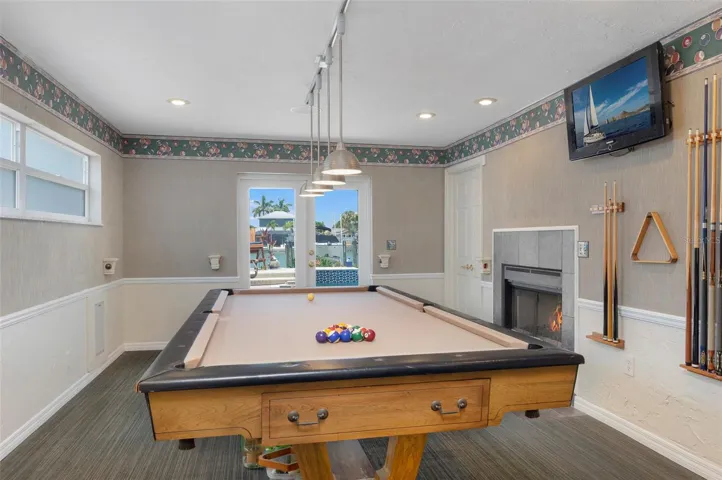 Family/game room has French doors leading to the pool - dual-sided fireplace, wet bar with fridge and flat screen tv