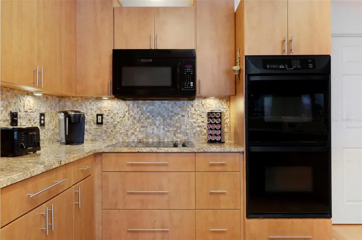 Kitchen with granite countertops and attractive stone backsplash