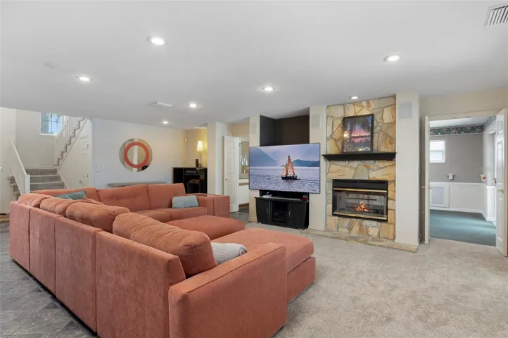 Main living area with dual-sided fireplace and view to adjacent family/game room