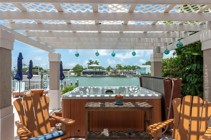 Shady hot tub and seating area overlooks the water