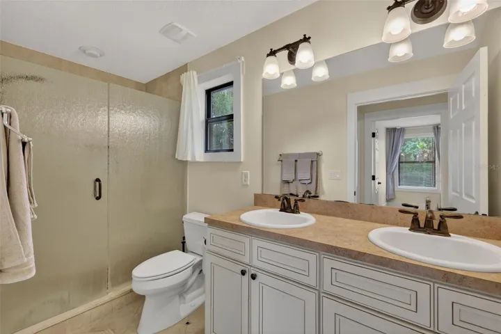 Bathroom in apartment with dual sinks, walk in shower