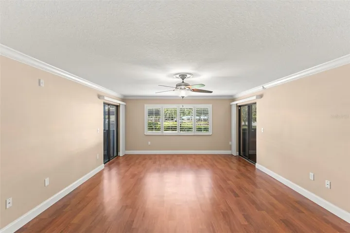 The spacious living room features crown molding, plantation shutters, wood-look flooring, and access to two enclosed porches that expand the home's living space.