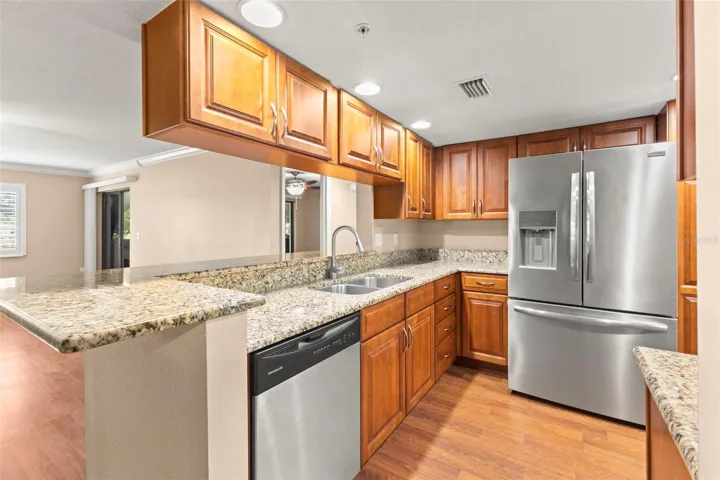 The open kitchen features granite countertops, extensive cabinet storage, stainless steel appliances, including a French-door refrigerator with water and ice dispensers, and a generous breakfast bar designed for both everyday use as well as entertaining.