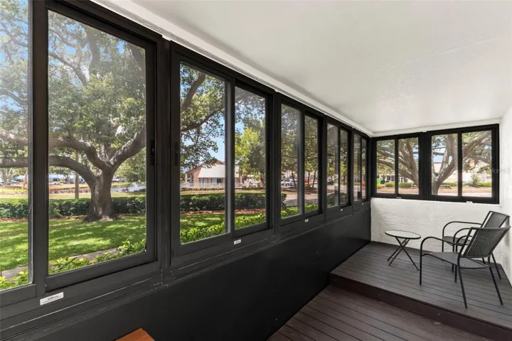 Spacious screened lanai featuring wall-to-wall windows and tranquil views of the beautifully maintained grounds.