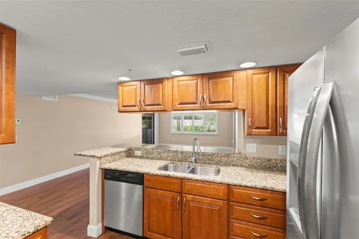 The open kitchen overlooks the living and dining areas and features a breakfast bar, stainless steel double sink, and seamless flow throughout the main living spaces.