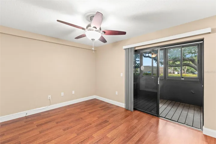 Versatile second bedroom with wood-look flooring, walk-in closet, and direct access to the screened lanai—ideal for guests, a home office, or hobbies.