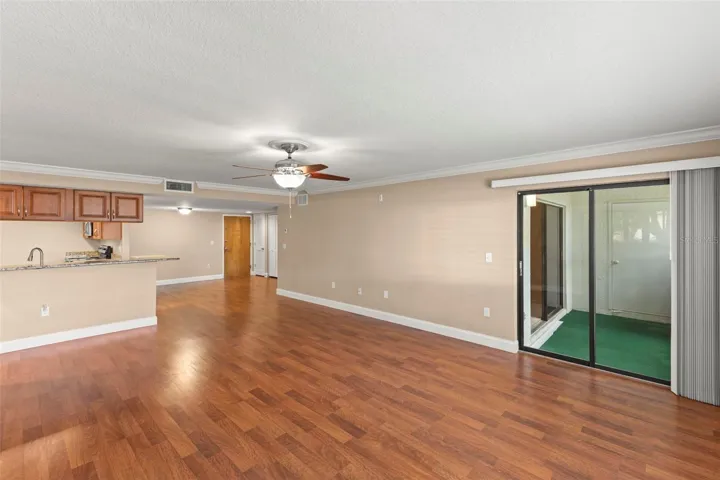 The open living and dining areas feature wood-look flooring, crown molding, a ceiling fan, and a neutral color palette that complements a variety of decorating styles.