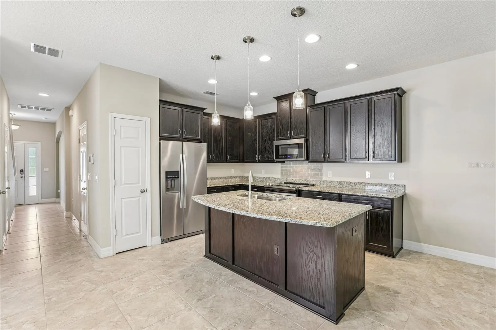 The OPEN CONCEPT main floor is designed for everyday living and easy entertaining, featuring a modern kitchen with rich cabinetry, GRANITE COUNTERTOPS, pantry storage, UPGRADED STAINLESS STEEL APPLIANCES, a large ISLAND with bar seating, pendant lighting, and recessed lighting.