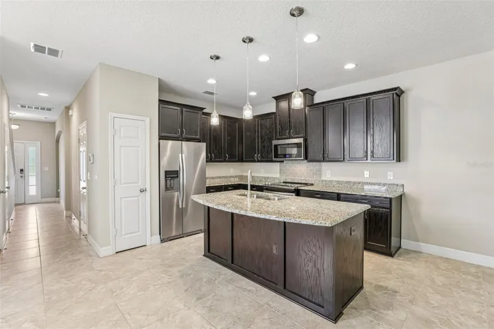 The OPEN CONCEPT main floor is designed for everyday living and easy entertaining, featuring a modern kitchen with rich cabinetry, GRANITE COUNTERTOPS, pantry storage, UPGRADED STAINLESS STEEL APPLIANCES, a large ISLAND with bar seating, pendant lighting, and recessed lighting.