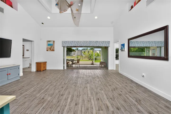 The living room features plank tiled flooring and sliding glass doors opening onto the lanai.