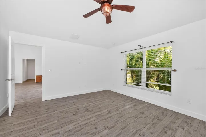 The primary bedroom features plank tiled flooring and a ceiling fan.