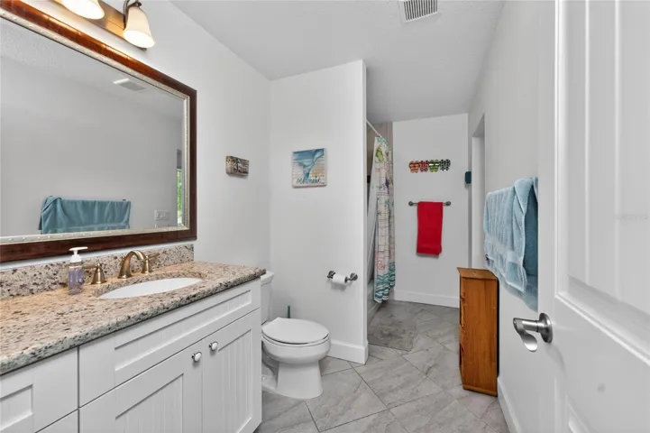 The guest bathroom features tiled flooring and a vanity with a granite countertop.