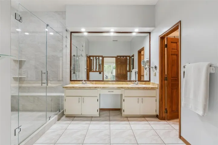 Primary ensuite bathroom.  Gorgeous remodeled shower with bench, with both a rain showerhead and a flexible showerhead.  Walk-in closet and separate linen closet