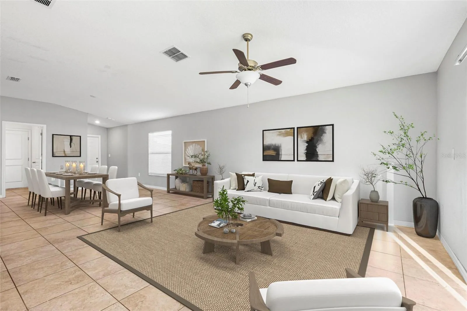 Great room featuring ceramic tile flooring, ceiling fan, and sliding glass doors that open to a fenced backyard, filling the space with natural light.