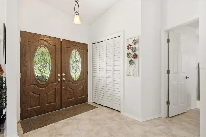 Step inside to a bright, welcoming foyer featuring elegant double front doors with decorative glass and high ceilings.