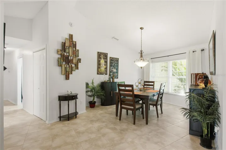 Elegant formal dining space featuring a striking hanging light fixture, large window for natural light, and plenty of room for hosting dinner parties.