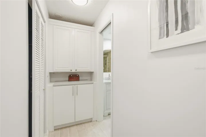 Primary suite hallway featuring custom built in cabinetry, with a his and her shared walk in closet to the left and the en suite bathroom to the right.