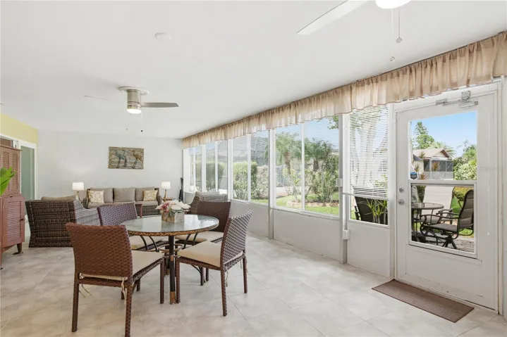 Altenate view of the massive Florida Room highlighting an abundance of hurricane proof windows overlooking the backyard, a cozy sitting area, and a glass door leading out to the rear patio.