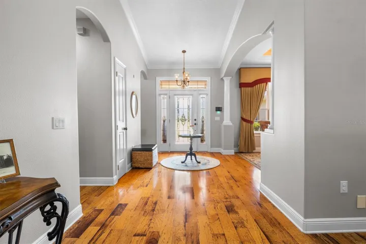 Entryway, wood flooring, open floor plan leading to dining room and living room