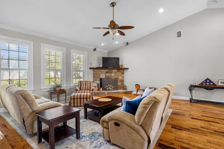 living room, gas fireplace, wood flooring, built in wet bar with sink, door leaving to patio, plantation shutters, high ceilings
