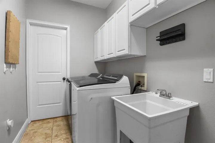Indoor laundry room, tile floors, storage cabinets, washroom sink. Door seen in photo leads to 5th bedroom