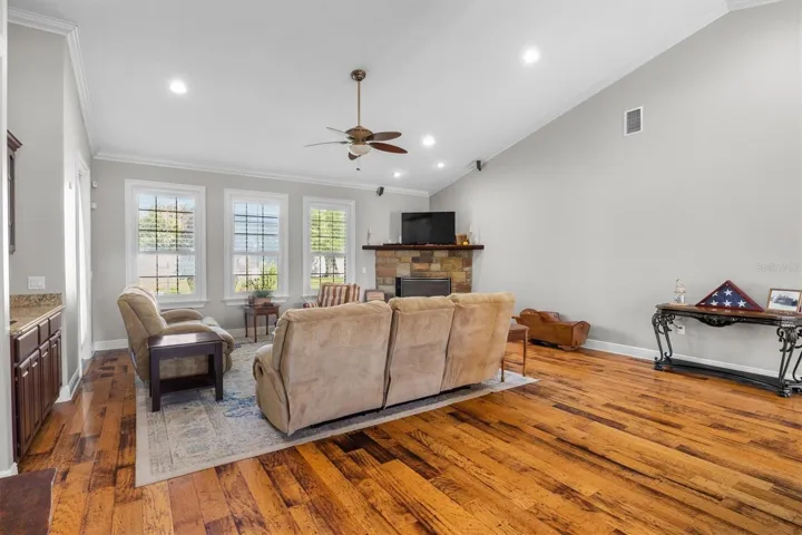 living room, gas fireplace, wood flooring, built in wet bar with sink, door leaving to patio, plantation shutters, high ceilings