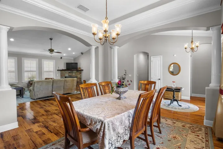 Dining room by entryway, tray ceiling, large windows, decorative columns, wood flooring, open floor plan leading to living room