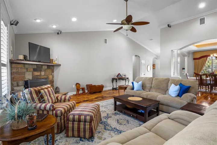 living room, gas fireplace, wood flooring, built in wet bar with sink, door leaving to patio, plantation shutters, high ceilings